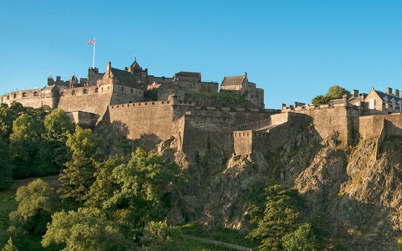 Discover Scotland Tour. Castle on cliff side overlooking valley below